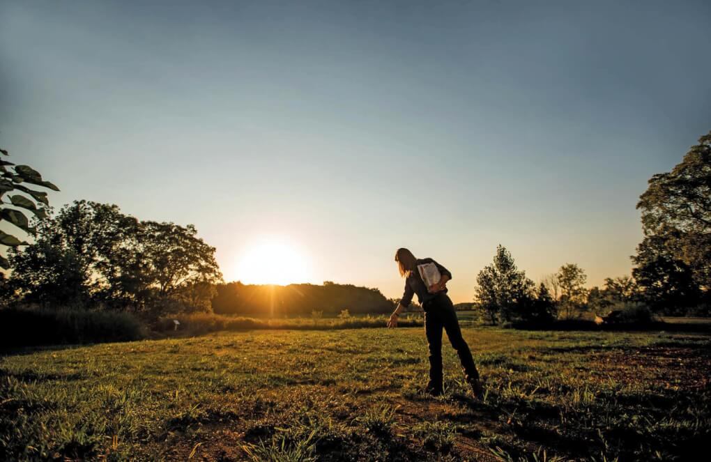 Woman spreads seeds in a field